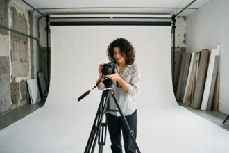 Intérieur d'un studio photo professionnel à Marseille avec cyclorama blanc et photographe féminine réglant son appareil sur trépied