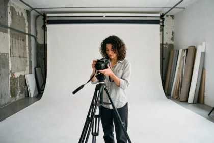 Intérieur d'un studio photo professionnel à Marseille avec cyclorama blanc et photographe féminine réglant son appareil sur trépied